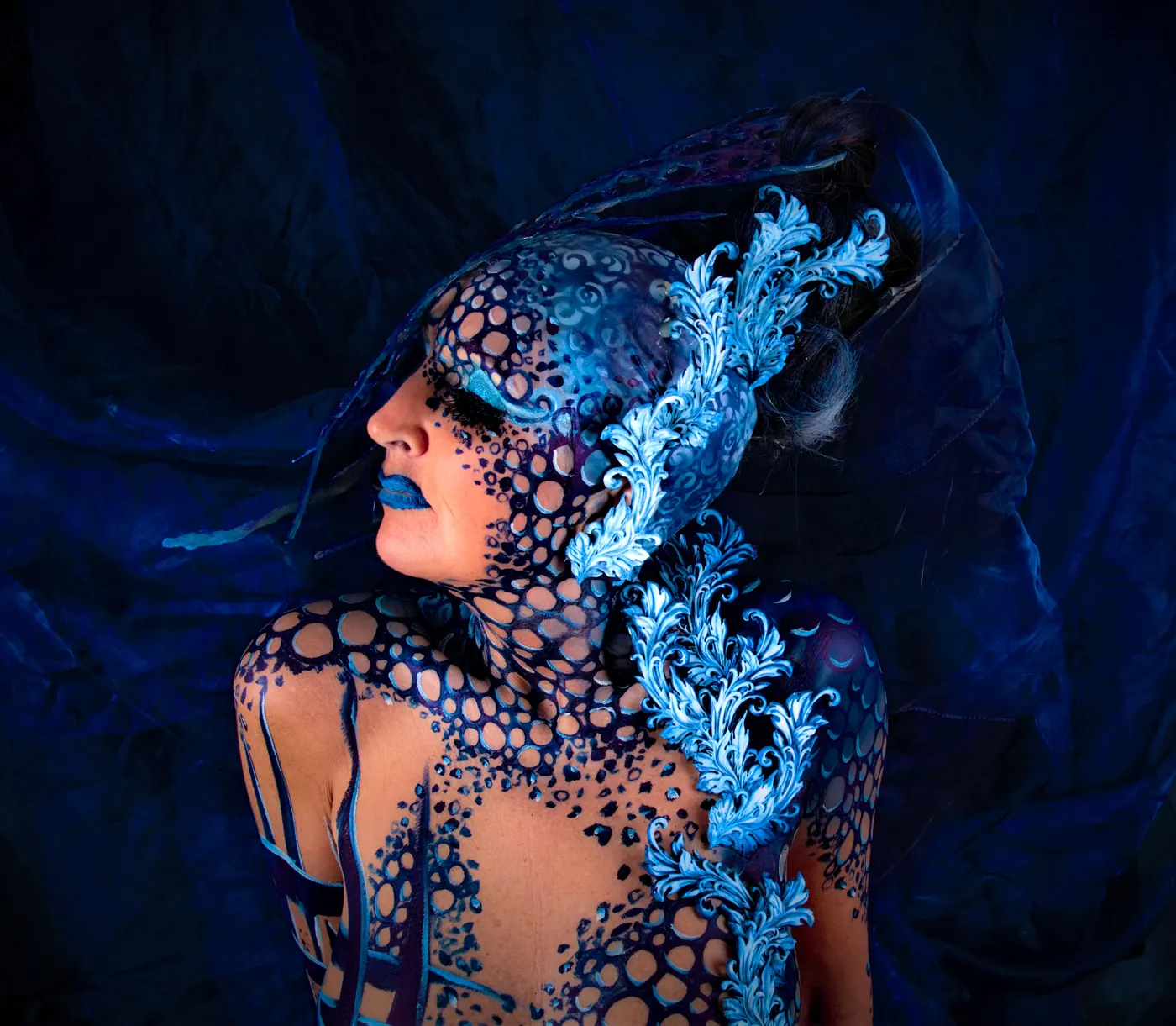 vrouw met blauwe bodypaint en ornamenten op torso