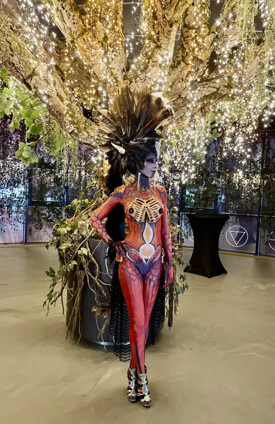 model in rode bodypaint met verentooi bij lichtboom