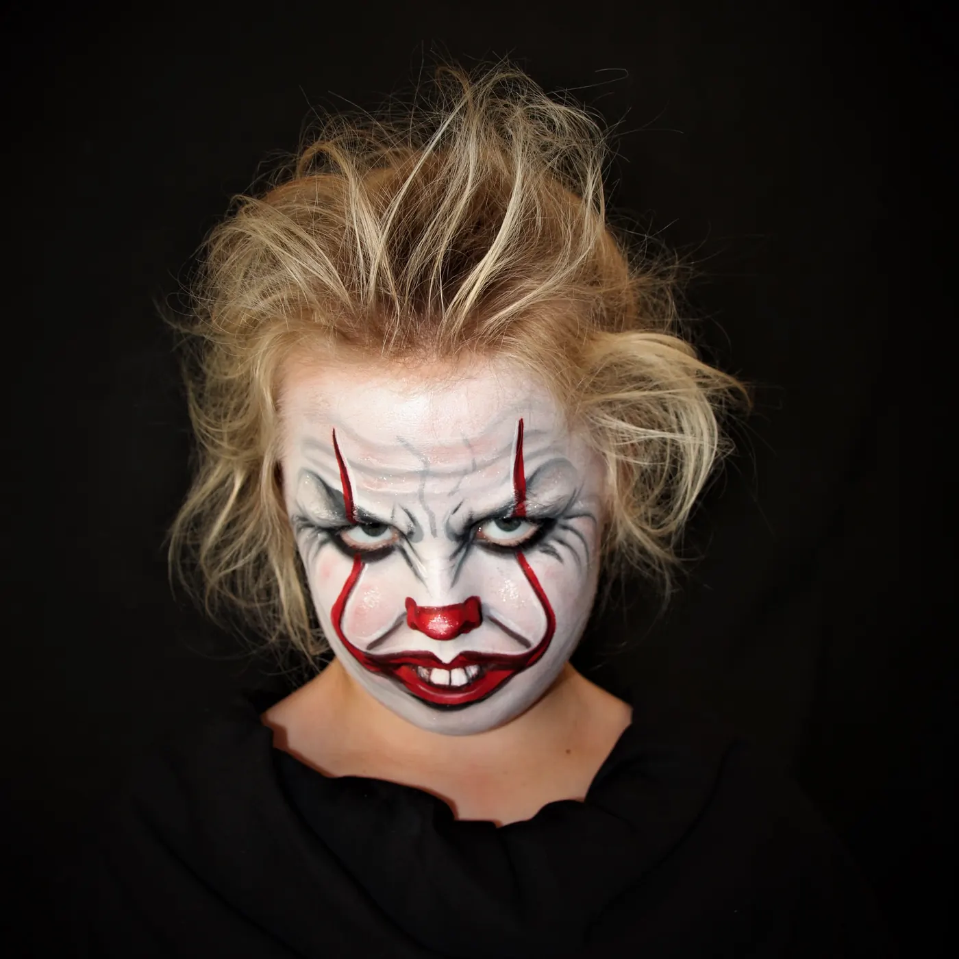 kind met witte clownschmink en rode strepen